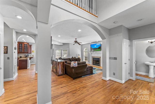 living area with baseboards, light wood-style flooring, recessed lighting, a tile fireplace, and ceiling fan