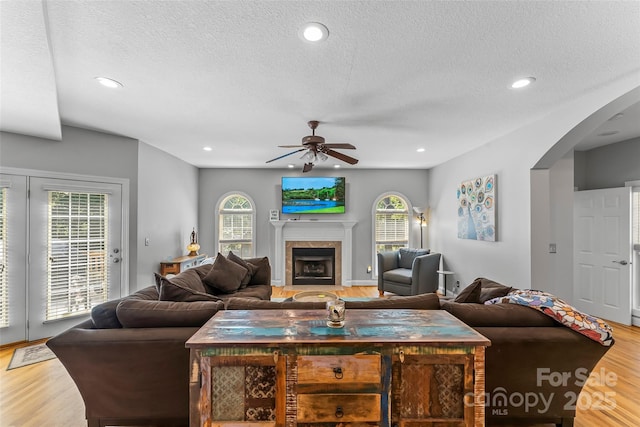 living area featuring a tiled fireplace, recessed lighting, wood finished floors, and a ceiling fan