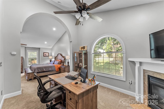 bedroom featuring baseboards, recessed lighting, arched walkways, a tile fireplace, and light carpet