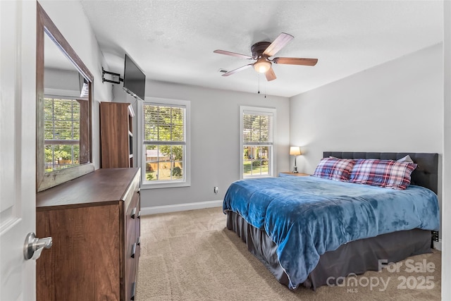 bedroom with multiple windows, light carpet, a textured ceiling, and baseboards