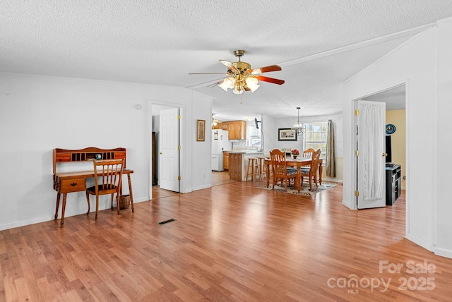 living area with light wood finished floors, ceiling fan with notable chandelier, a textured ceiling, and baseboards