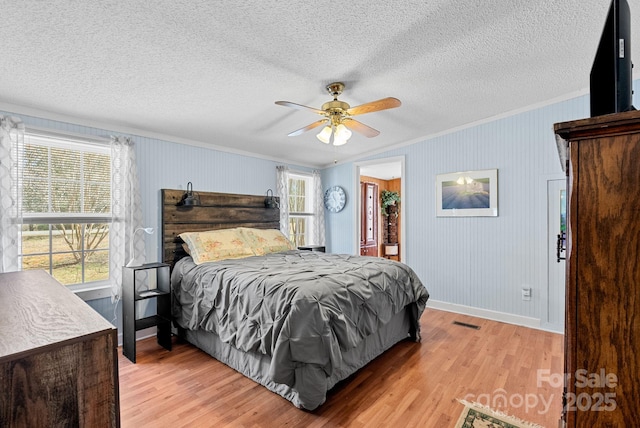 bedroom with visible vents, crown molding, a textured ceiling, and light wood-type flooring