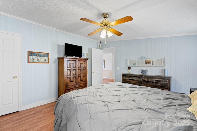 bedroom featuring crown molding, baseboards, wood finished floors, a textured ceiling, and a ceiling fan