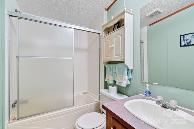 bathroom featuring vanity, visible vents, shower / bath combination with glass door, a textured ceiling, and toilet