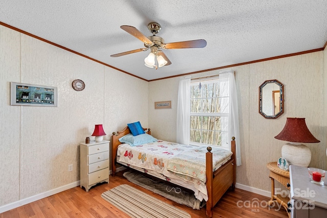 bedroom featuring light wood-type flooring, a textured ceiling, and crown molding