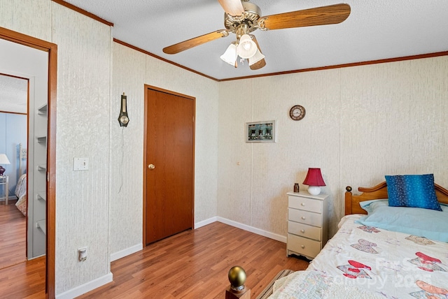 bedroom featuring a ceiling fan, crown molding, wood finished floors, and baseboards