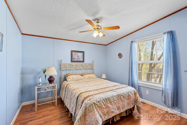 bedroom featuring ceiling fan, a textured ceiling, wood finished floors, and crown molding