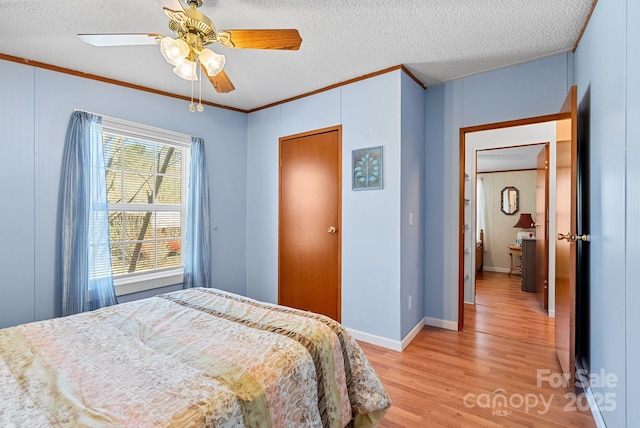 bedroom with light wood finished floors, baseboards, ornamental molding, a textured ceiling, and a ceiling fan