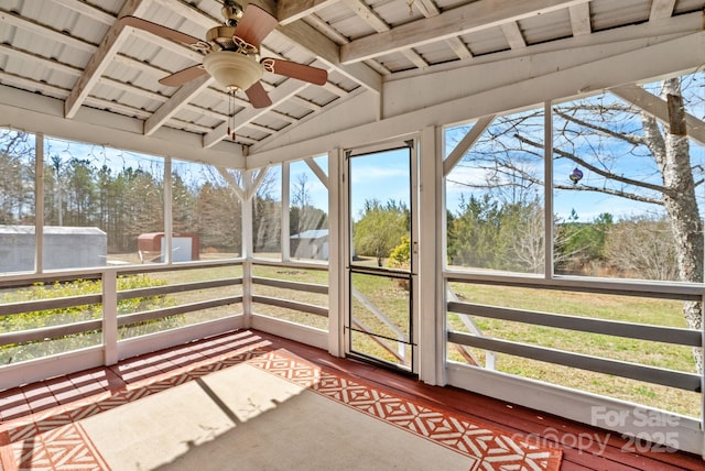 sunroom with lofted ceiling with beams and ceiling fan