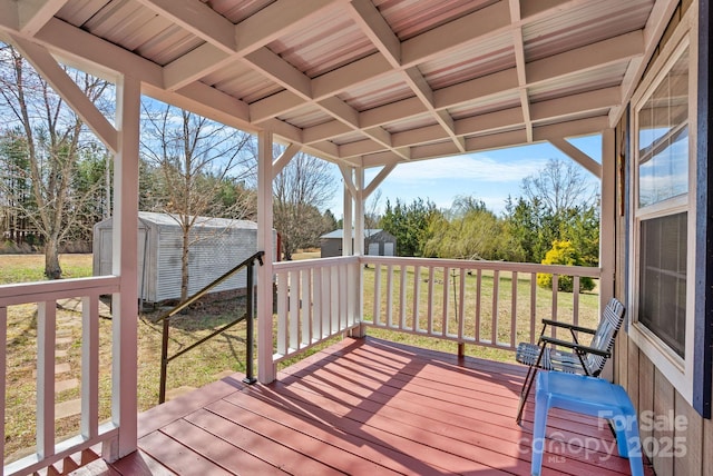 wooden terrace with an outbuilding, a lawn, and a storage shed