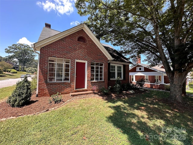 view of front of property with brick siding, a front lawn, and a chimney