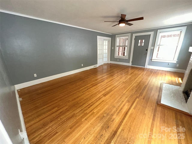 unfurnished living room with light wood-style floors, baseboards, a ceiling fan, and ornamental molding