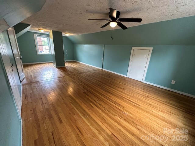 additional living space featuring a textured ceiling, ceiling fan, lofted ceiling, baseboards, and wood-type flooring