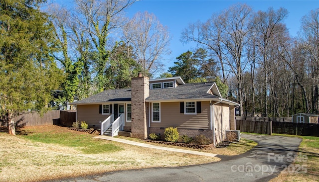 view of front of house with fence, a front yard, a chimney, crawl space, and driveway