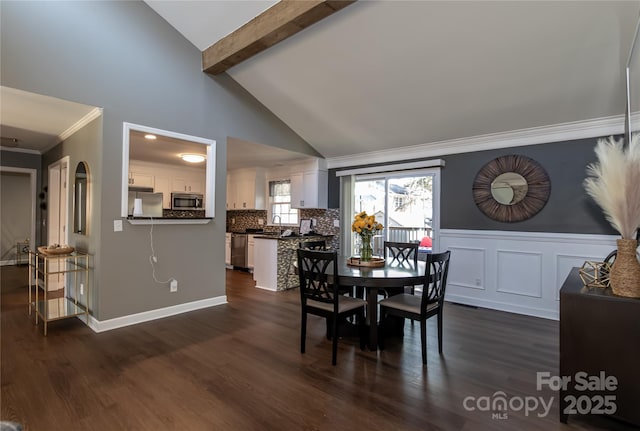 dining space with lofted ceiling with beams, a wainscoted wall, dark wood-style floors, and ornamental molding