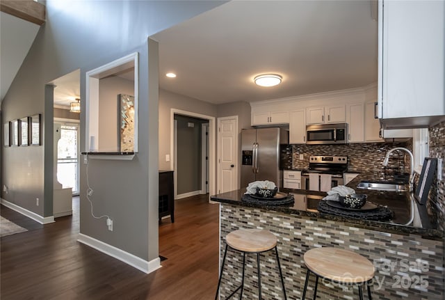 kitchen with dark wood-style floors, a sink, appliances with stainless steel finishes, white cabinetry, and backsplash