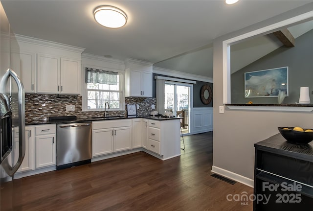 kitchen featuring dark countertops, stainless steel appliances, crown molding, and a sink