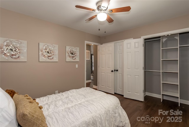 bedroom featuring ceiling fan, baseboards, two closets, and dark wood finished floors