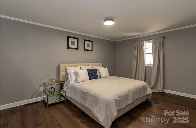 bedroom featuring baseboards, wood finished floors, visible vents, and ornamental molding