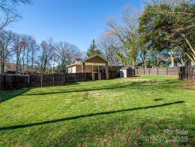 view of yard with a storage unit, an outbuilding, and a fenced backyard