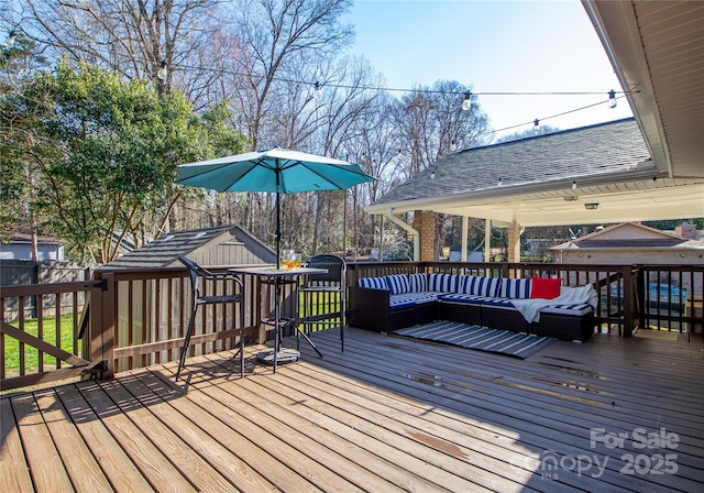 wooden terrace with an outdoor living space, an outbuilding, and fence