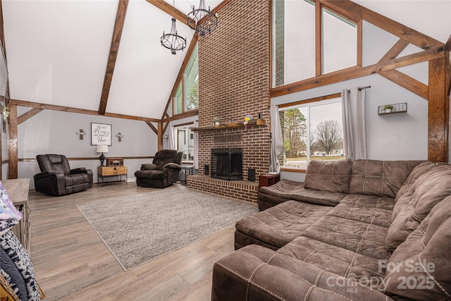 living room with high vaulted ceiling, a brick fireplace, beamed ceiling, and wood finished floors