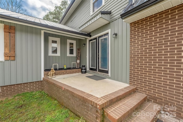 view of exterior entry with brick siding and metal roof