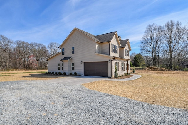 view of side of home with a garage, driveway, and brick siding