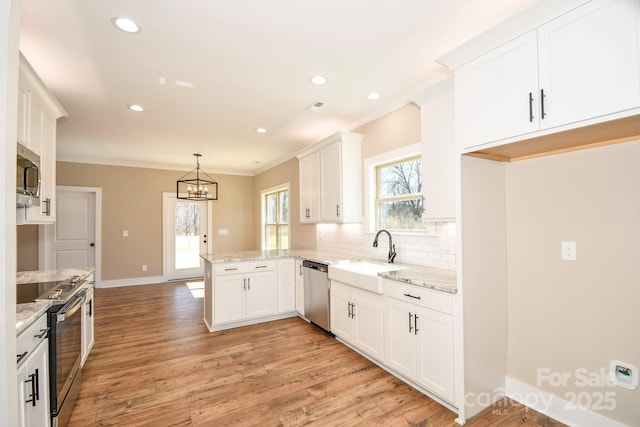 kitchen with appliances with stainless steel finishes, white cabinetry, a peninsula, and decorative backsplash