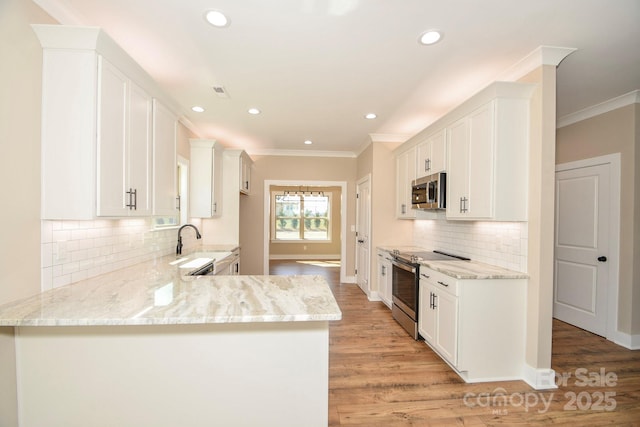 kitchen featuring stainless steel appliances, ornamental molding, a peninsula, and light stone counters