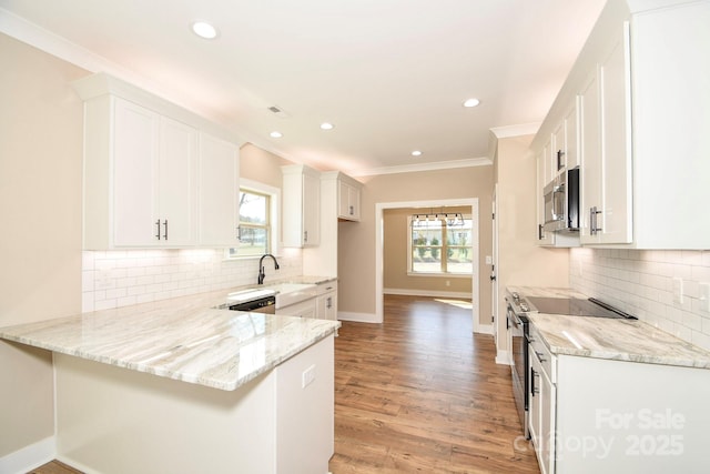 kitchen featuring stainless steel appliances, white cabinets, a peninsula, and light stone countertops