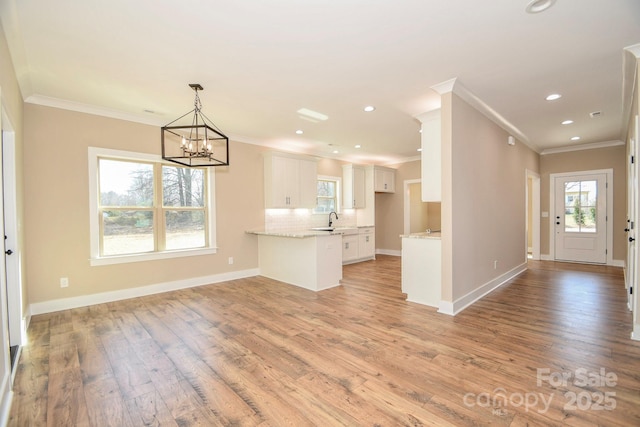 kitchen with a peninsula, light wood-type flooring, white cabinetry, and a wealth of natural light