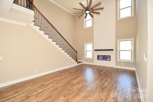 unfurnished living room featuring baseboards, a fireplace, stairway, and wood finished floors