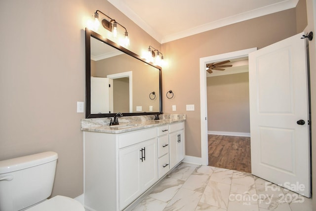 bathroom with marble finish floor, crown molding, toilet, a sink, and baseboards