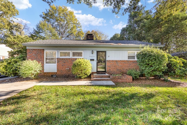 ranch-style house with a front yard, brick siding, and a chimney