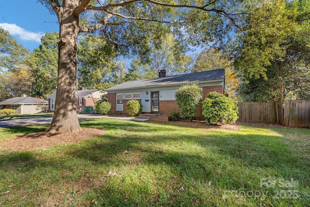 view of front of house featuring a chimney, fence, a front lawn, and brick siding