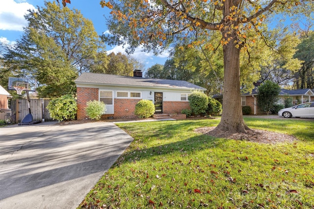 ranch-style house featuring brick siding, a chimney, a front yard, and fence