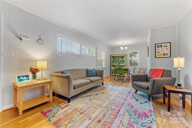 living area featuring light wood-style floors, a chandelier, and crown molding