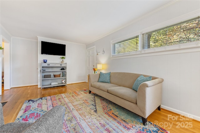 living room with crown molding, baseboards, and wood finished floors