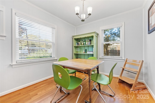 dining space featuring a chandelier, light wood finished floors, ornamental molding, and baseboards