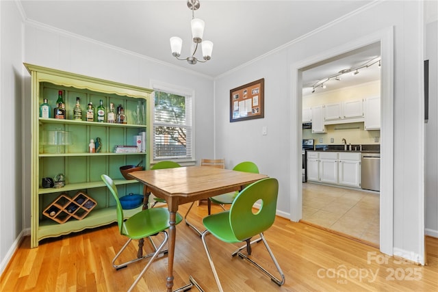 dining room with light wood-style floors, baseboards, crown molding, and an inviting chandelier