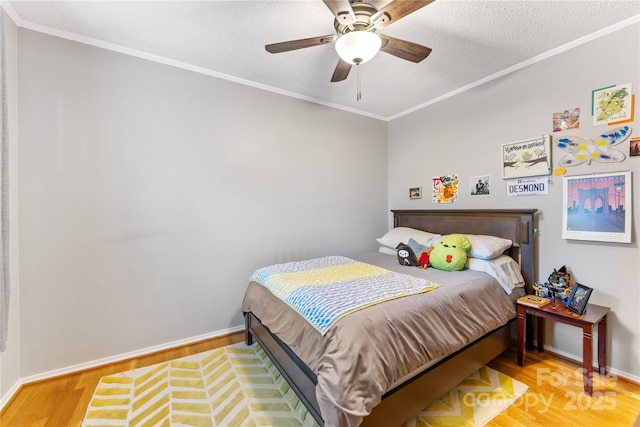 bedroom with baseboards, a textured ceiling, wood finished floors, and crown molding