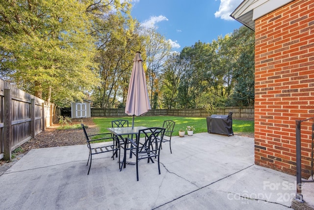 view of patio with a storage shed, a fenced backyard, outdoor dining area, and an outbuilding