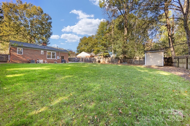 view of yard featuring a storage shed, a fenced backyard, central AC unit, and an outbuilding