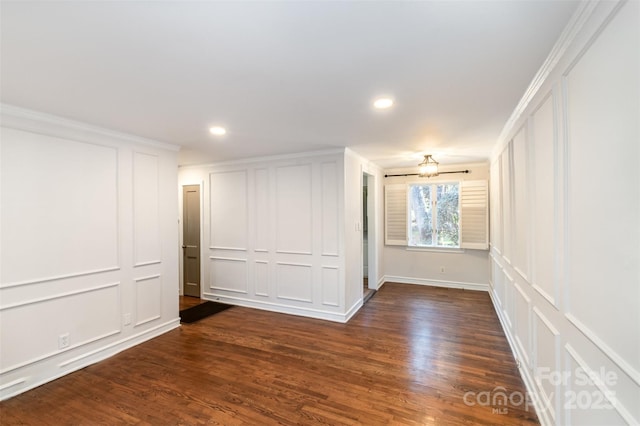 unfurnished room with dark wood-type flooring, recessed lighting, a decorative wall, and ornamental molding