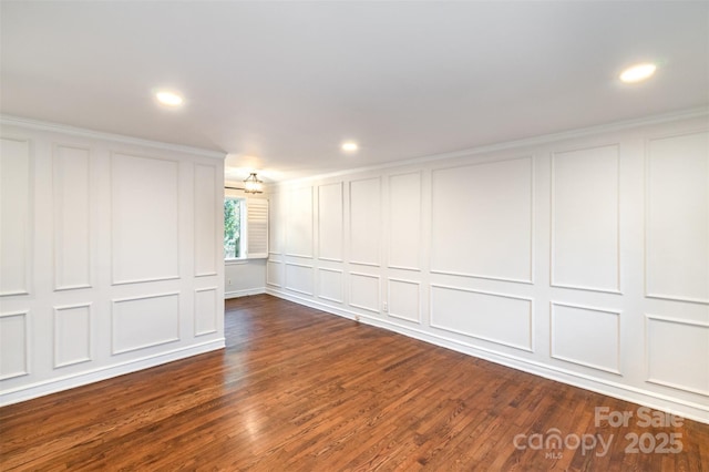 spare room with dark wood-style floors, a decorative wall, and recessed lighting