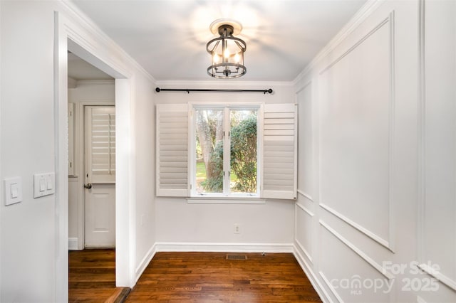 unfurnished dining area featuring visible vents, baseboards, dark wood-type flooring, an inviting chandelier, and crown molding