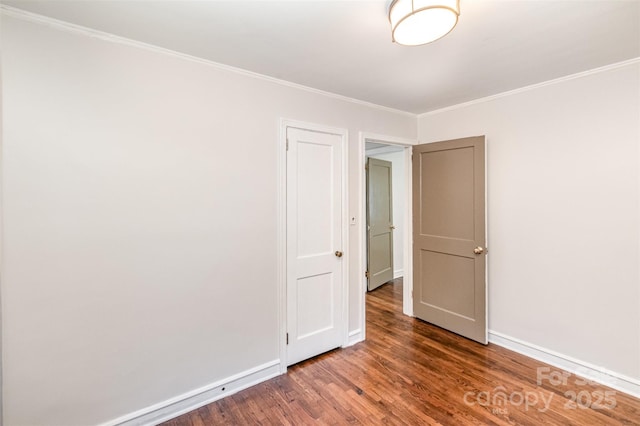 spare room featuring crown molding, wood finished floors, and baseboards