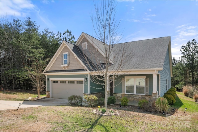 craftsman-style house featuring stone siding, a front lawn, roof with shingles, and driveway