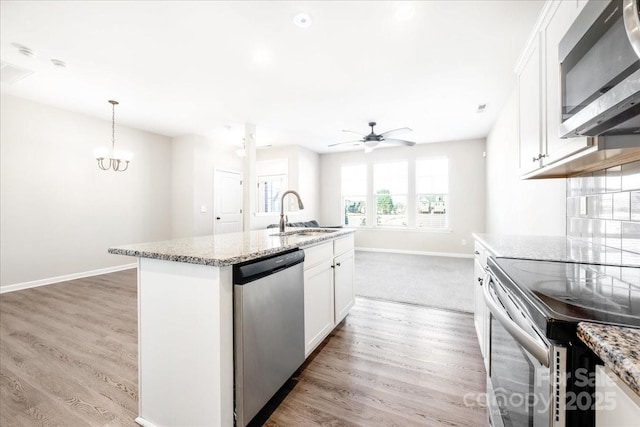 kitchen featuring appliances with stainless steel finishes, light wood-type flooring, a sink, and light stone countertops